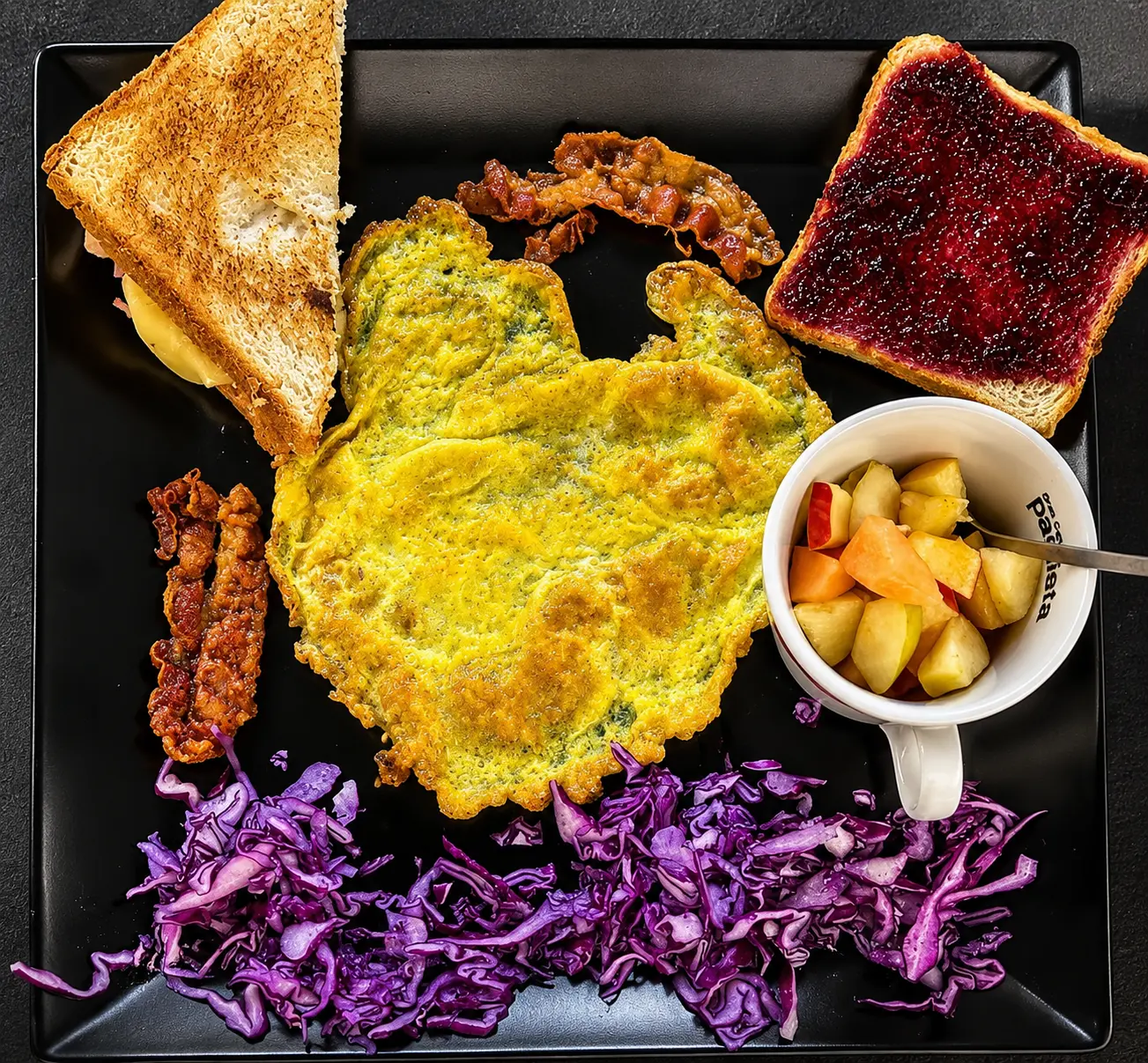 Colazione salata con omelette, toast, bacon e frutta fresca